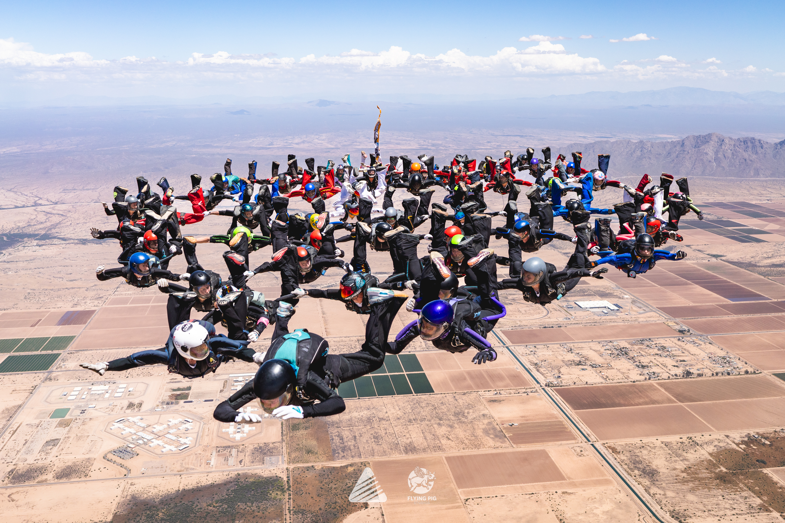 Large group of skydivers gathered in formation above the Arizona desert