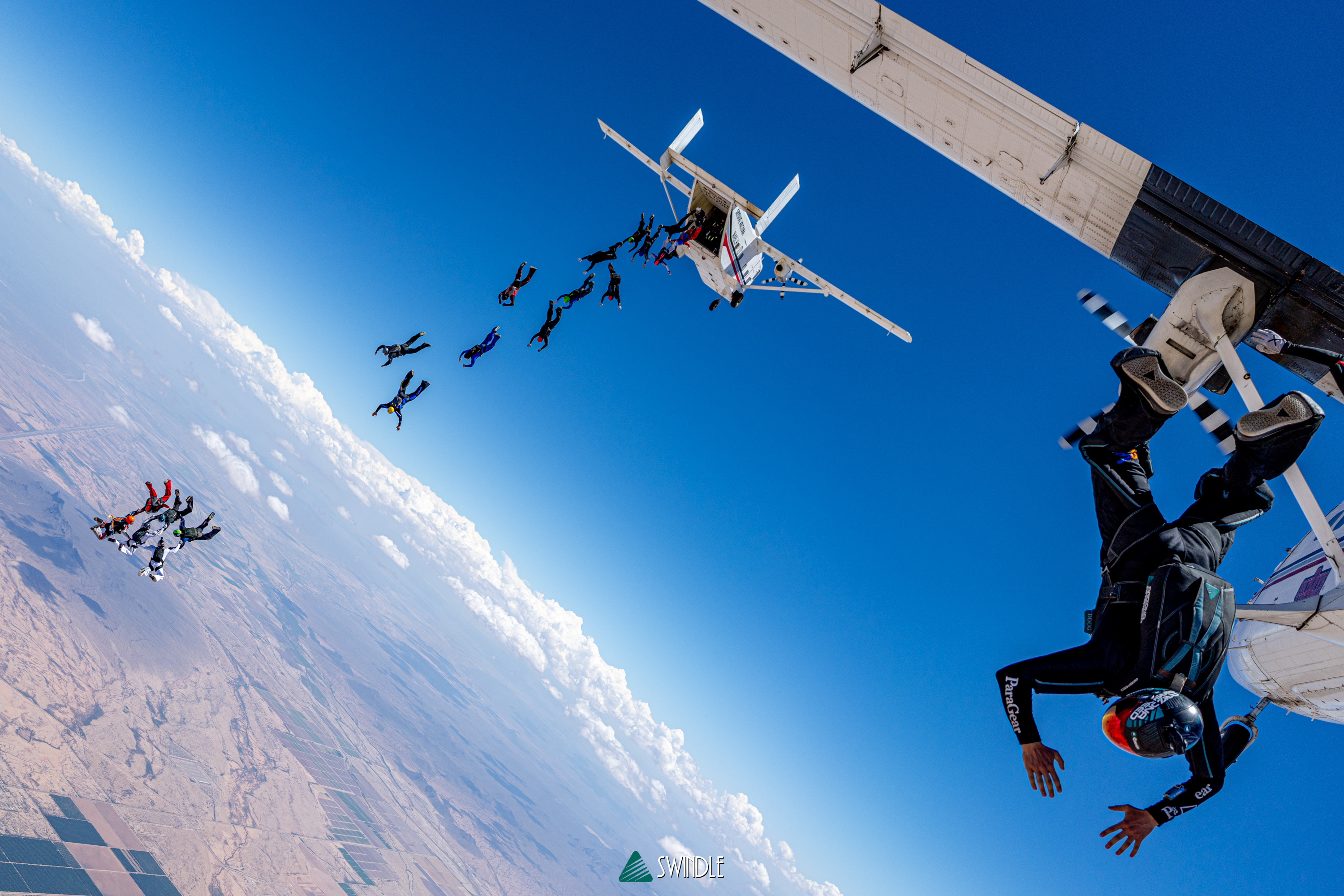 Skydivers exiting a jump plane above the Arizona desert with Doug Hendrix on the right