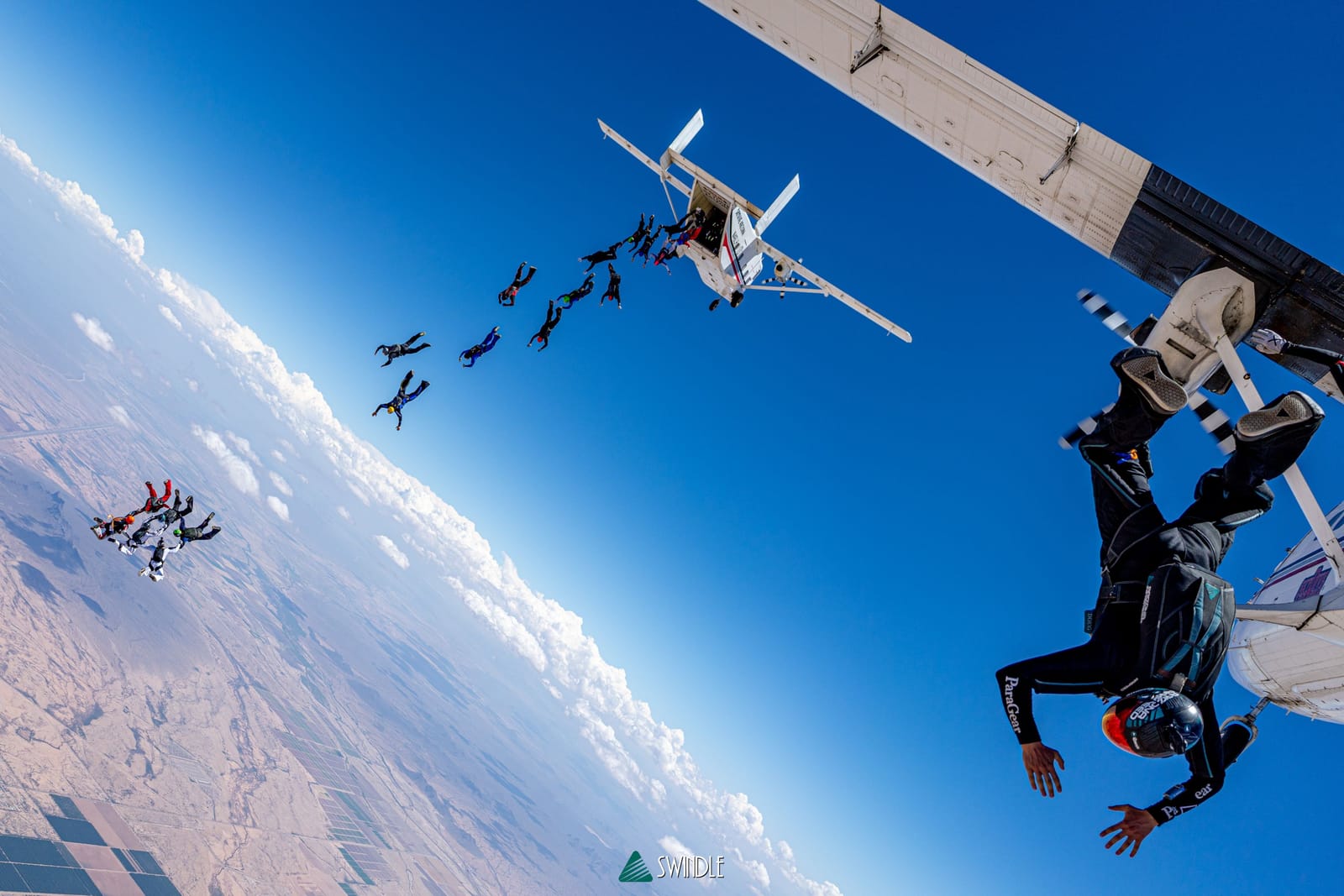 Skydivers exiting a jump plane above the Arizona desert with Doug Hendrix on the right